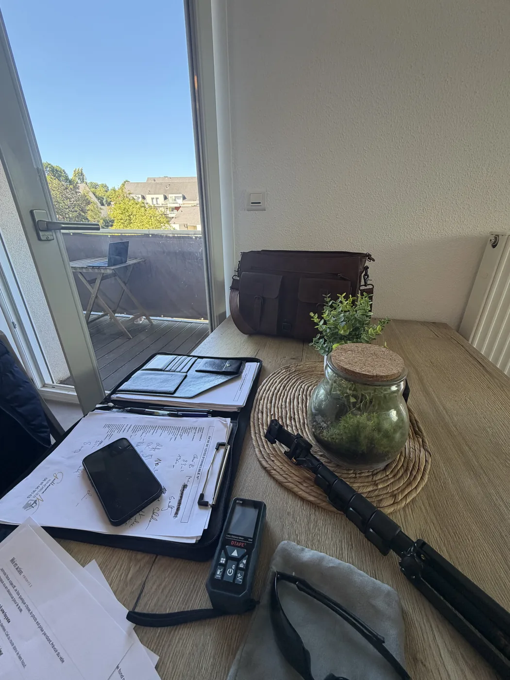 Dossier d'estimation, télémètre laser et documents de visite sur une table